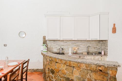 a kitchen with white cabinets and a stone counter top at Casa P - Relax nel verde a Ezzi Minori in Cuile Ezi Mannu