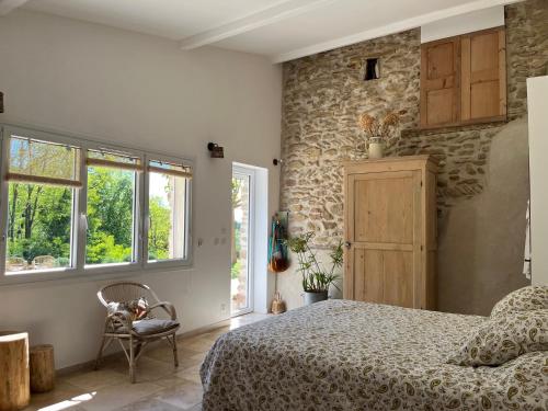 a bedroom with a bed and a stone wall at La Clairière de l'Ange Havre de paix en Drôme des Collines in Peyrins
