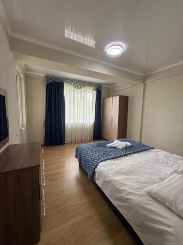 a bedroom with a large bed and a dresser in it at Танхаус Коттедж in Bosteri