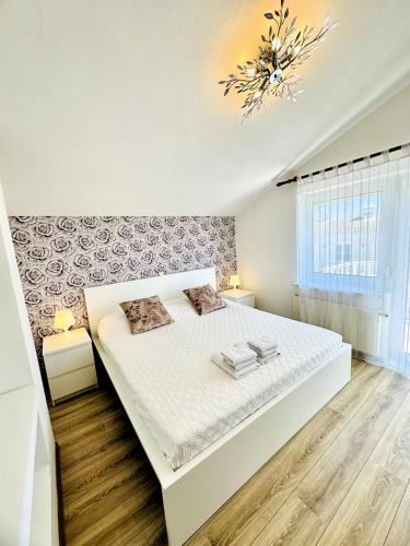 a bedroom with a large white bed and a chandelier at Maja - Apartment 1 in Funtana