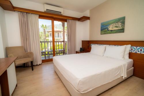 a bedroom with a white bed and a balcony at Hotel Lotus Spa&Sport Akyaka in Akyaka