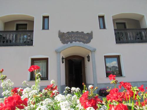 a white building with red flowers in front of it at Residence Du Chateau in Fenis