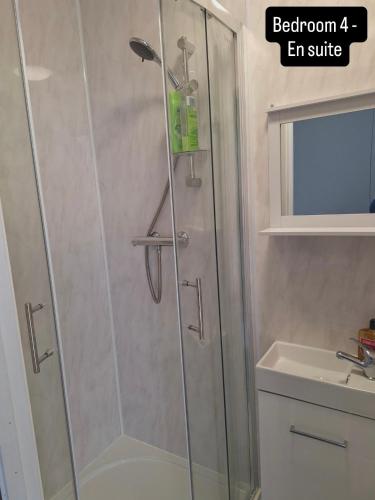 a shower with a glass door next to a sink at The Queens Hotel in Rhondda
