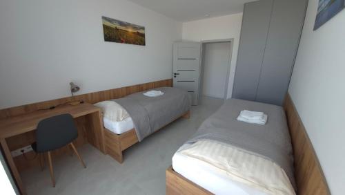 a bedroom with two beds and a desk and a chair at Apartman Bartimej 3 in Bobrów