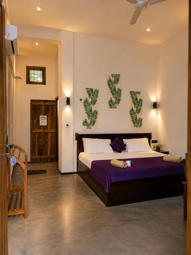 a bedroom with a large bed with purple sheets at One FS Hotel Arugambay in Arugam Bay