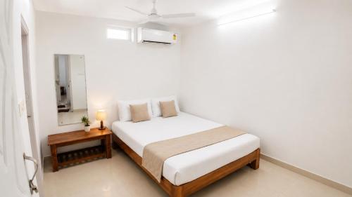 a white bedroom with a bed and a table at Gardens by Lotels in Madambakkam