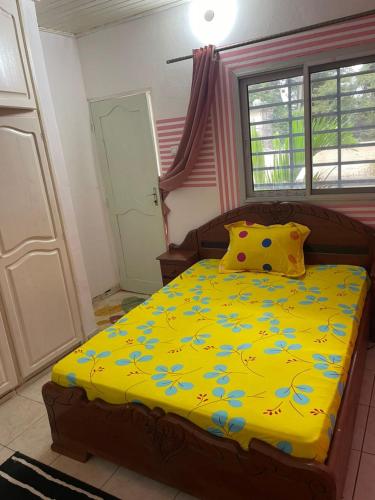 a bedroom with a bed with a yellow blanket at Villa le Dakota la différence in Yaoundé