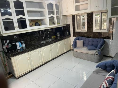 a kitchen with white cabinets and a chair and a sink at Villa le Dakota la différence in Yaoundé