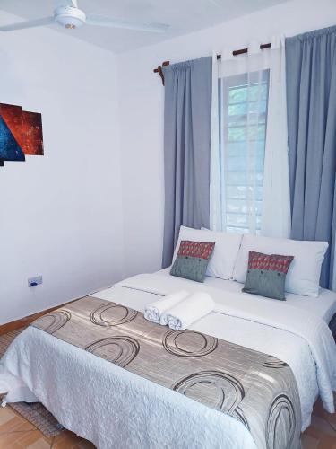 a bedroom with a large white bed with a window at Devkim Stays-Cozy Comfort Near The Beach in Ukunda
