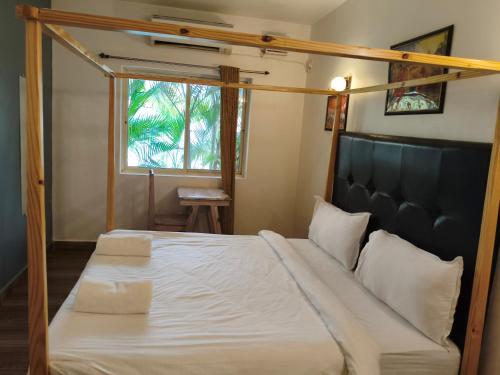 a bedroom with a bed with white sheets and a window at Rajdeep by Dacha Arambol in Arambol