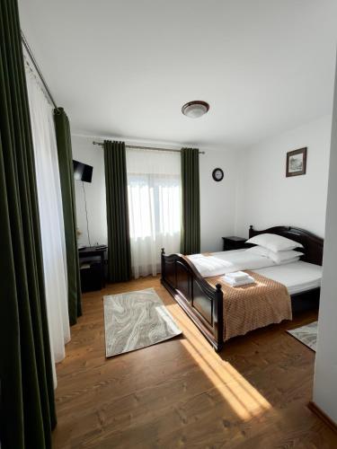 a bedroom with a bed in a room with green curtains at Casa Corlățeni in Pojorâta