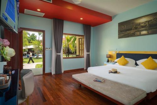 a bedroom with a large white bed with yellow pillows at Habana Angkor Resort in Siem Reap