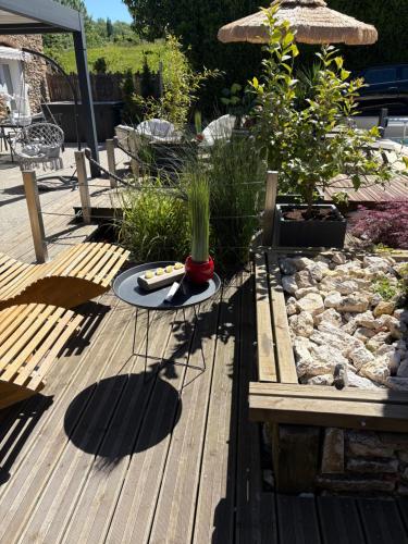 a wooden deck with a table and some plants at Les chambres dhotes de la croix bleue 2 in Murinais