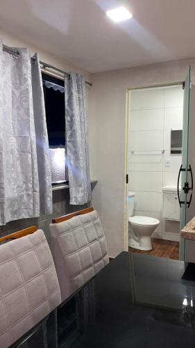 a bathroom with a toilet and a glass shower door at Hospedagem e pizzaria florestinha in Búzios