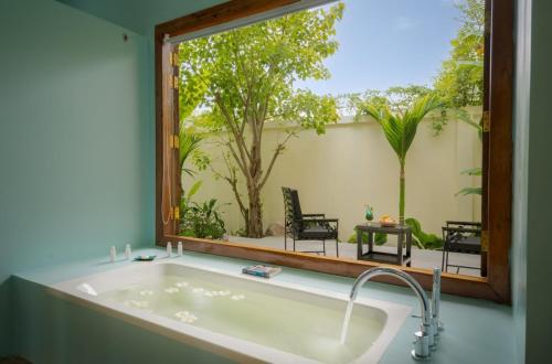 a bath tub in a room with a large window at Habana Angkor Resort in Siem Reap