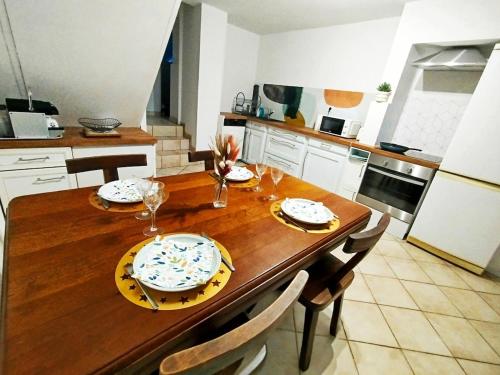 a kitchen with a wooden table with plates and glasses at Gîte Mézilles location sem-we in Mézilles