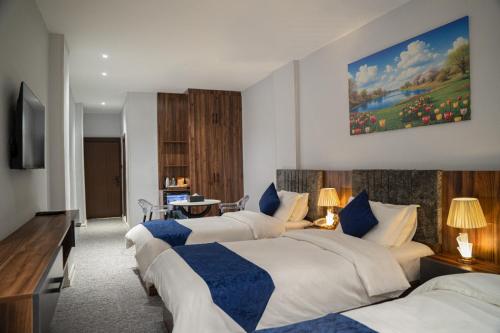 a hotel room with three beds and a painting on the wall at Burj Al Salam Hotel in Al ‘Alwīyah