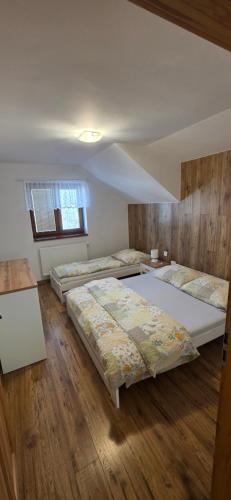two beds in a room with wooden floors at Chalupa Chotár in Terchová
