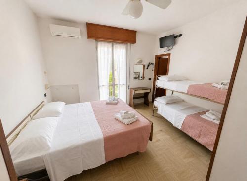 a hotel room with two beds and a mirror at Hotel Podgora Nuova Gestione in Rimini