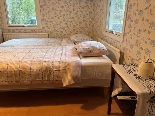 a bedroom with a bed and two windows at Nyrenoverad stuga mellan två sjöar in Järlåsa