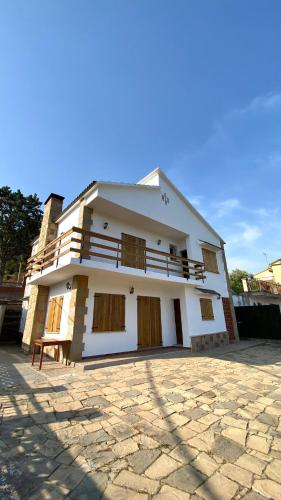 a large white house with a stone ground in front of it at La Casa de la Vall in Castellbell i Vilar
