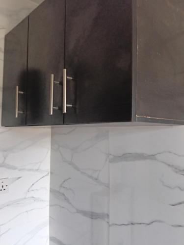 a kitchen with black cabinets and marble counter tops at Bec property in Ikorodu