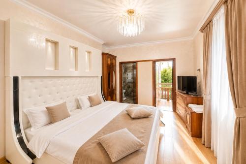 a bedroom with a large white bed and a television at Old Yerevan by IGIT in Yerevan