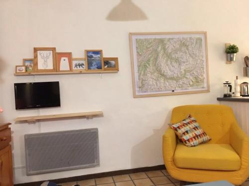 uma sala de estar com uma cadeira amarela e uma televisão em Jour De Peuf em Champagny-en-Vanoise