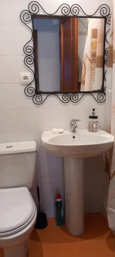 a bathroom with a sink and a toilet and a mirror at Rincón de Candelaria in Solórzano