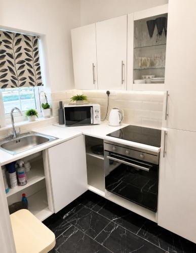 a white kitchen with a sink and a microwave at The lodge in Rushbrooke
