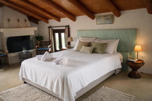 a bedroom with a large white bed with towels on it at Villa Amalthia Panorama in Bozikás