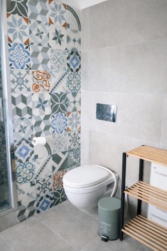 a bathroom with a toilet and tiles on the wall at Villa Amalthia Panorama in Bozikás