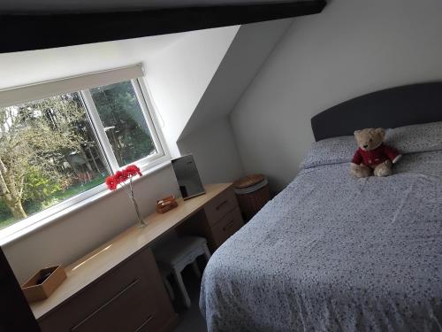 a teddy bear sitting on a bed in a bedroom at Tudor Cottage, Newby Bridge in Ulverston