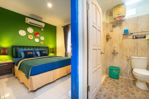 a bedroom with a bed and a toilet and green walls at Roemah Noni Baciro By ARBA in Demangan
