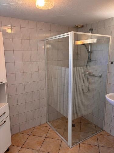 a shower with a glass door in a bathroom at Seestern 61 in Julianadorp