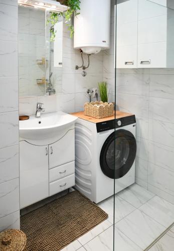 a white bathroom with a washing machine and a sink at Apratman Shine Kula in Kula
