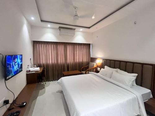 a hotel room with a large bed and a television at MRP Residency in Chitradurga