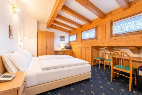 a hotel room with a bed and a desk and chairs at Pineta Pastry Hotel in Rocca Pietore