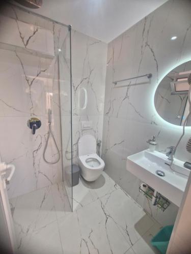 a white bathroom with a toilet and a sink at Dream Seaview Apartment INI in Íshulli i Tetranisit
