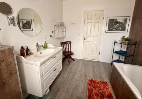 a bathroom with a sink and a mirror and a tub at Nýlenda - Charming Two Bedroom Seaside Property, Mountain and Town Views in Seyðisfjörður