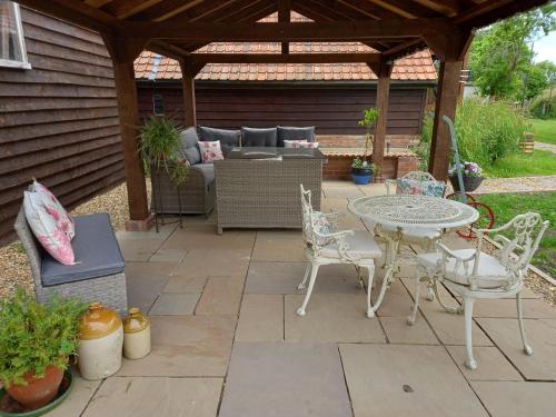 a patio with a table and chairs under a pergola at Rustic Retreat Guest Lodge in Littleport