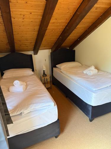 two beds in a room with wooden ceilings at Cozy Attic in Berkach