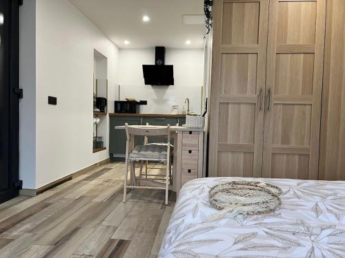 a bedroom with a bed and a desk and a kitchen at Studio au Fil de l'eau in Langatte
