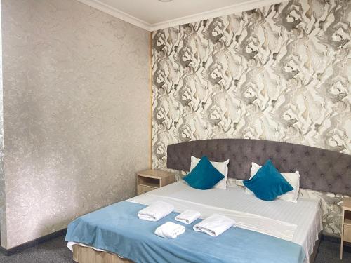 a bedroom with a bed with blue and white pillows at GLOBUS Avenue Hotel in Yakkasaray