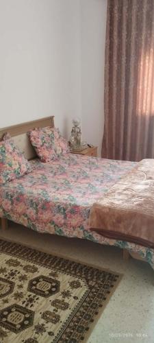 a bedroom with a bed with a floral comforter at Appartement 24 in Sousse