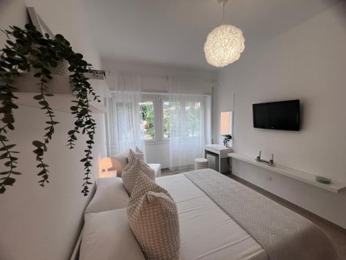 a white bedroom with a bed and a tv at TERRACINA Central Rooms in Terracina