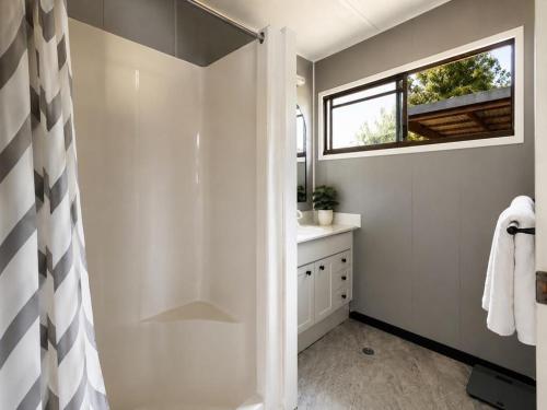 a white bathroom with a shower and a window at The Cove - Lake Eildon in Piries