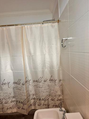 a bathroom with a shower curtain with writing on it at Apart Boutique EL DESCANSO in Libertador General San Martín