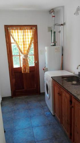 a kitchen with a washing machine and a door at Casas Altas VGB in Villa General Belgrano