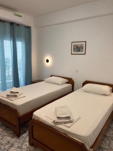 two beds in a room with blue curtains at Indigo sea view rooms in Olympic Beach